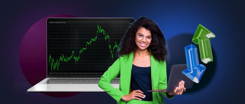 A forex trader holding a laptop in front of a computer screen showing a stock chart