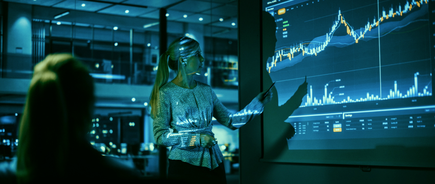 A female trader examines a screen filled with graphs comparing fundamental and technical trading approaches.