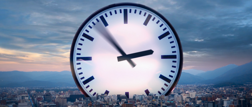 A clock displays the time in front of a city skyline, symbolizing market hours for forex trading.