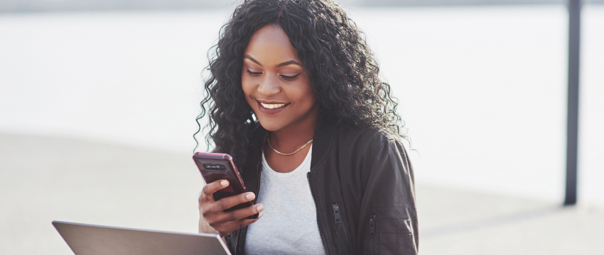 A trader smiles while using her phone, conveying a sense of joy and engagement with her trading platform