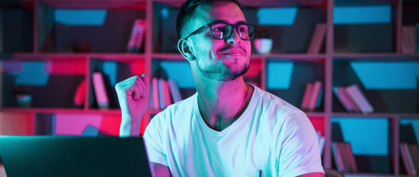 A man with glasses is seated at a laptop, engaged in a demo practice for forex trading success.