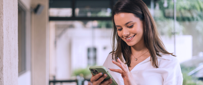 A woman smiles while using her phone, actively participating in forex trading events and news updates.
