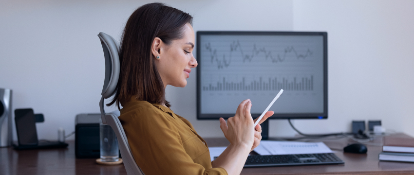 A woman at her desk, using a tablet computer, exemplifying a fundamental trader in action.